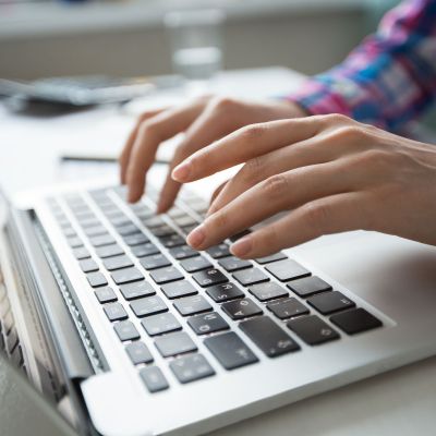Cropped View of Hands Typing on Laptop